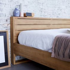 the bed is made and ready to be used as a nightstand or night stand with a framed photograph on it