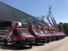 a row of red trucks parked next to each other in front of a large building