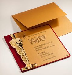 a red and gold card with an oscar statue on the front, and a golden envelope