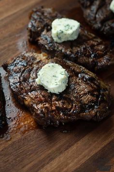 steaks with blue cheese on top sitting on a cutting board