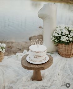 a white cake sitting on top of a wooden table next to some baskets filled with flowers