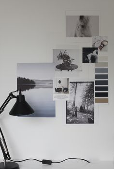 a desk lamp sitting on top of a table next to a wall covered in pictures