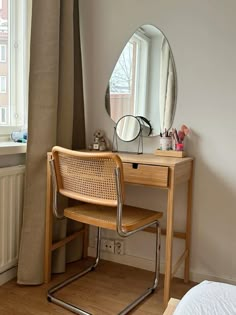 a desk with a mirror and chair in front of a window next to a bed