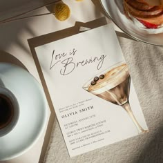 there is a card that says love is brewing next to a cup of coffee and cake