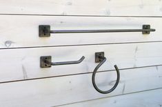 two metal hooks are attached to the side of a white wooden wall with wood planks