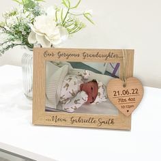 a wooden frame with a baby's photo and a heart hanging from the side