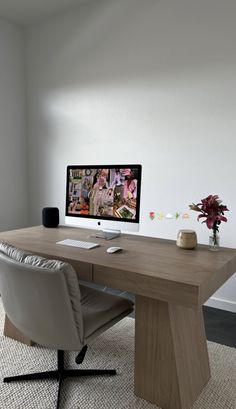 a desk with a computer on it in front of a white wall and carpeted floor