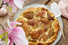 an apple pie on a plate with pink flowers and utensils next to it