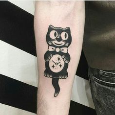 a black and white cat with a clock tattoo on its arm