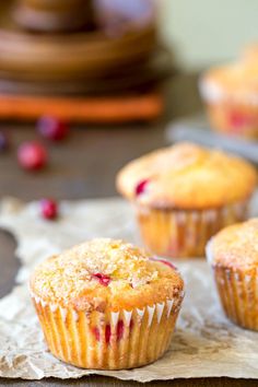 three muffins sitting on top of a table next to some cranberries