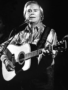 a man holding a guitar while standing in front of a microphone