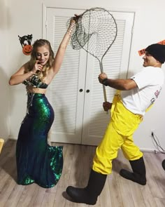 a man and woman dressed up in costumes, one is holding a net while the other holds