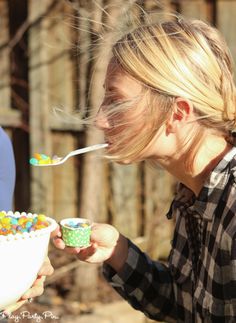 a woman eating cereal from a bowl while holding a spoon with candy in her mouth