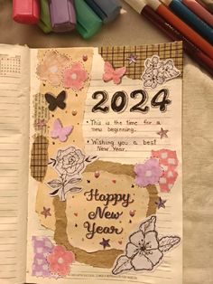 an open notebook with the words happy new year written on it next to colored crayons