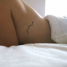 a woman with a tattoo on her stomach laying in bed