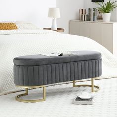 a bedroom with a bed, nightstands and an ottoman on the floor in front of it