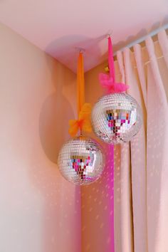 two disco balls hanging from the ceiling in a pink room with curtains and drapes