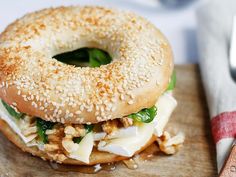 a sesame seed bagel sandwich on a wooden cutting board