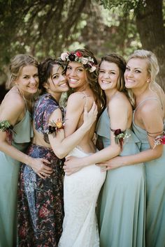 a group of women standing next to each other in front of a forest filled with trees