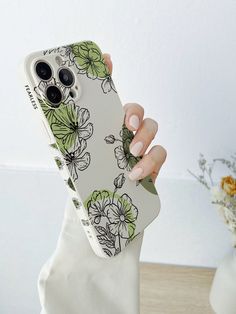 a woman holding up her phone case with flowers on it