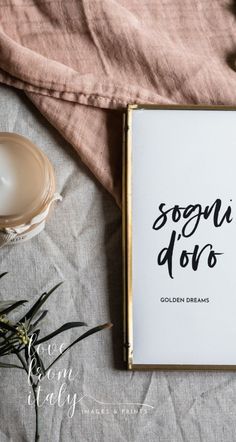 an open book sitting on top of a bed next to a cup and saucer