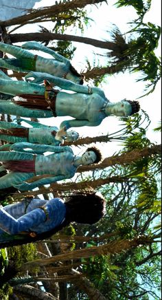 several wooden dolls hanging from the branches of trees