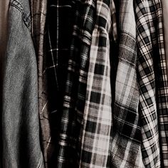 several shirts hanging on a rack in the dark