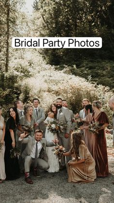 a group of people standing around each other in front of some trees and bushes with flowers