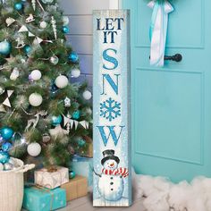 a wooden sign that says let it snow next to a christmas tree