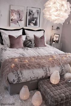 a bedroom with white and gray decor and lights on the headboard, bedding, and footstools