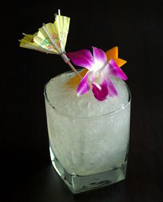 a drink in a glass with an umbrella sticking out of the top, on a black surface