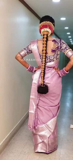 a woman in a pink sari with long braids on her head and hands behind her back