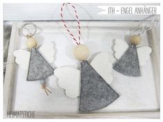 three felt angel ornaments in a box with red and white twine on the string