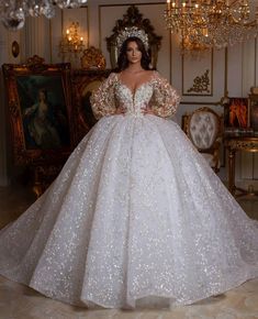 a woman in a white wedding dress standing next to a chandelier