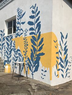 a yellow cow painted on the side of a white building with blue and yellow leaves