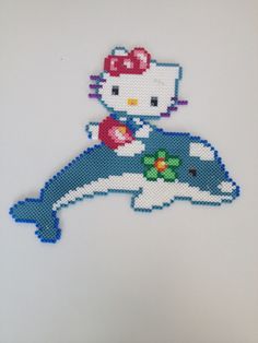 the hello kitty is sitting on top of a dolphin with a flower in it's mouth