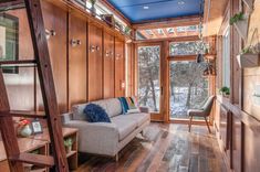 a living room with wood paneling and blue painted ceiling, along with a ladder leading up to the second floor