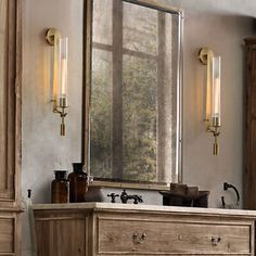 a bathroom vanity with a large mirror above it and lights on the wall next to it