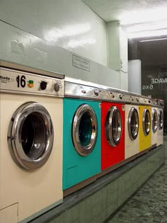 a row of colorful washing machines in a public washroom