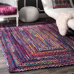 a living room with white furniture and colorful rugs