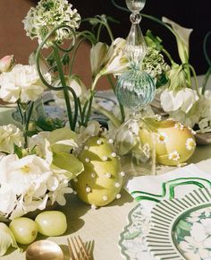 a table topped with lots of white flowers next to green and yellow plates on top of a table