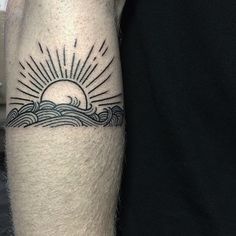 a man's arm with a sun and waves tattoo on it, in black and white