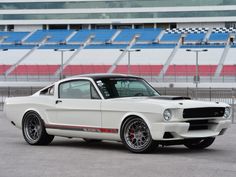 a white mustang parked in front of a stadium