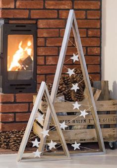 two wooden christmas trees sitting in front of a fire place with white stars on them