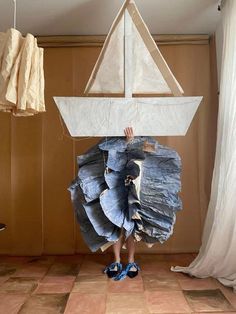 a person standing in front of a sailboat made out of old blue jean pants