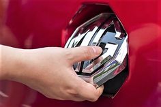 a person's hand is pressing the button on a red car