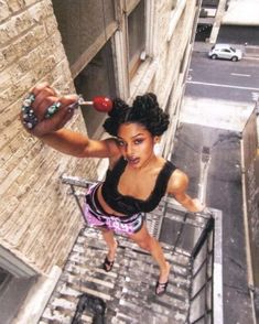 a woman in black top and purple shorts standing on stairs with an object in her hand