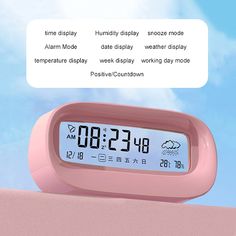 a pink alarm clock sitting on top of a table next to a cloud filled sky