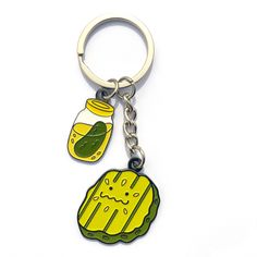 a yellow keychain with a pickle and jar on the front, sitting on a white surface