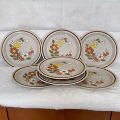 a set of five plates sitting on top of a white towel next to a wooden cabinet